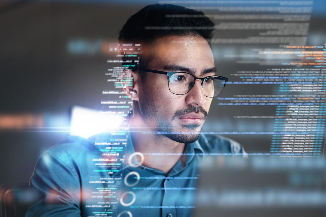 Man in glasses lit by the glow of a screen